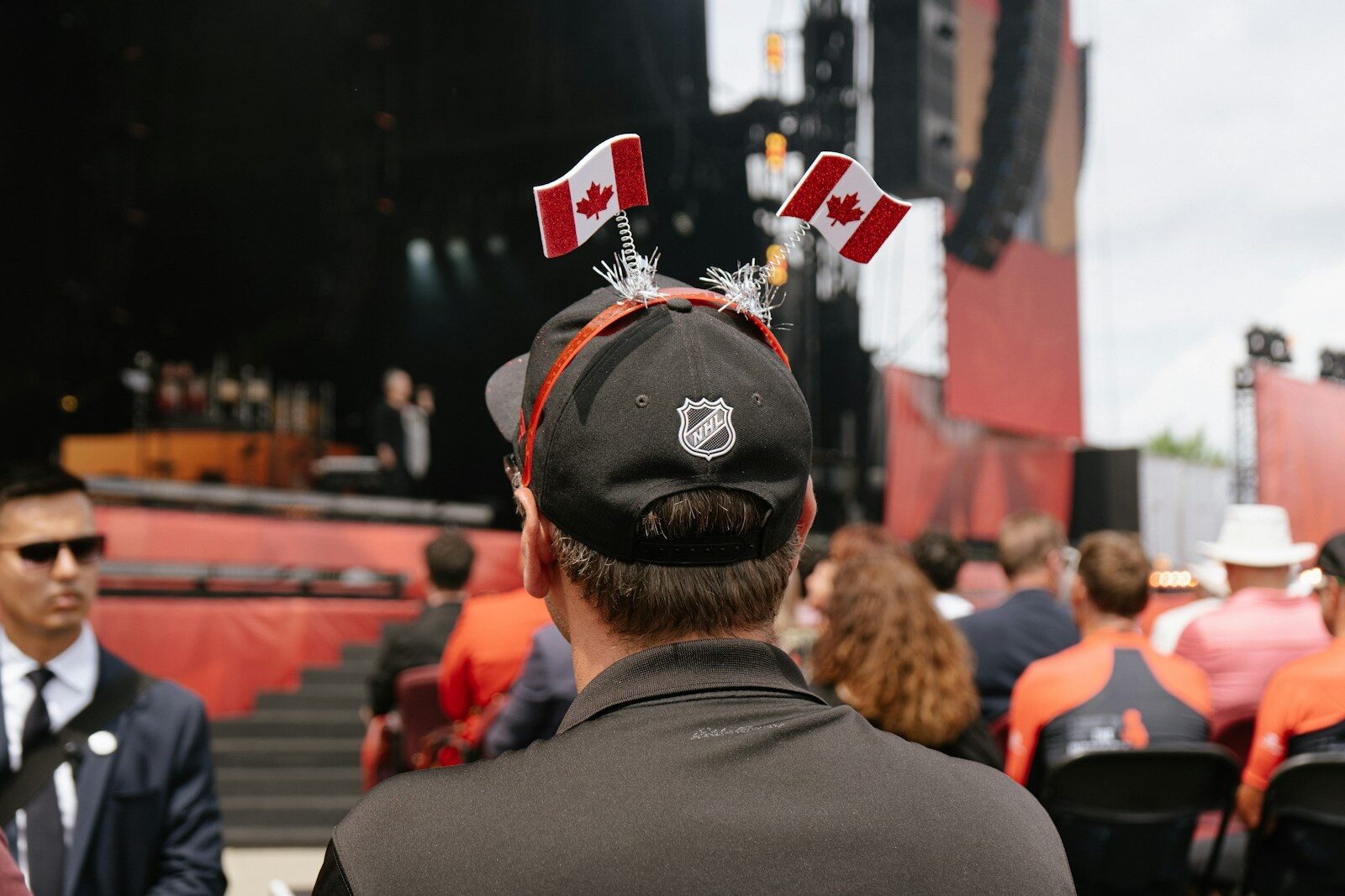 Someone wears a hat with canadian flags at a concert.
