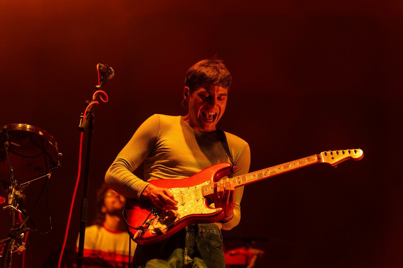 A man playing a guitar in front of a microphone
